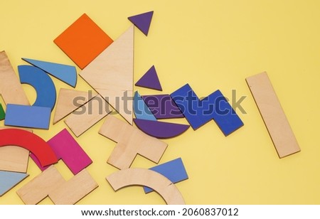 used tangram game pieces placed chaotic on a wooden board.colorful puzzle pieces. green, violet, pink, orange. iq games, intelligence and educational jigsaw game
