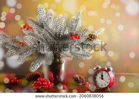 The clock shows the approach of the holiday against the background of fir branches. Christmas card.