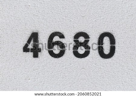 Black Number 4680 on the white wall. Spray paint. Number four thousand six hundred and eighty.