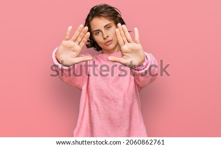 Young hispanic woman wearing casual clothes doing frame using hands palms and fingers, camera perspective 