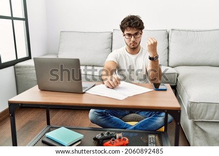 Hispanic man doing papers at home doing italian gesture with hand and fingers confident expression 