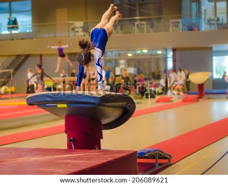 Young gymnast girl performing jump on a vault while practicing for the competition Royalty-Free Stock Photo #206089621