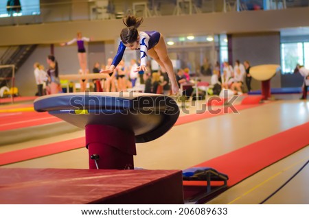 Young gymnast girl performing jump on a vault while practicing for the competition Royalty-Free Stock Photo #206089633