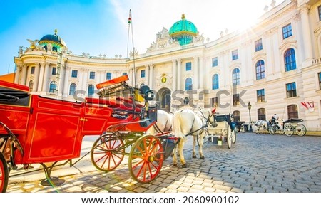 Hofburg palace and horse carriage on sunny Vienna street, Austria travel photo. Hofburg palace is royal family a residence in Vienna.