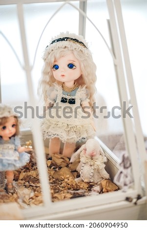 Cute doll. Adorable innocent looking doll wearing vintage apron is on display at doll shop. Beside her is a white rabbit mohair doll. Vintage style. Soft focus on the eye.