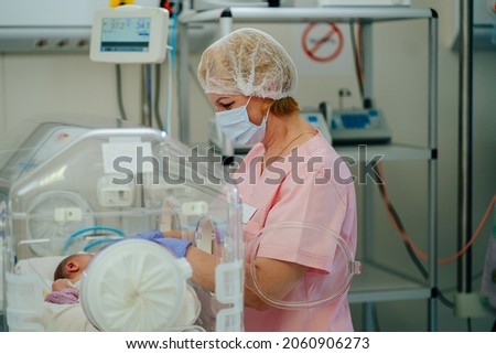 At the intensive care unit. Nurse standing near hospital bed with a baby preparing it for treatment. Newborn is placed in the incubator. Neonatal intensive care unit Royalty-Free Stock Photo #2060906273