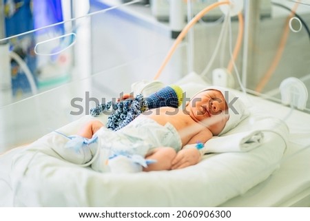 Two-day-old newborn baby boy in intensive care unit in a medical incubator. Newborn rescue concept. The work of resuscitation doctors. Photo indoors. Royalty-Free Stock Photo #2060906300