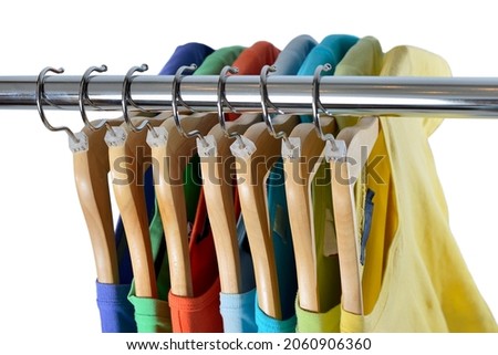 T-shirts of different colors hang on closing rack on wooden hangers are isolated on white background. View from above
