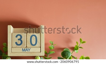 May 30, Date design with calendar cube and leaf on orange background.