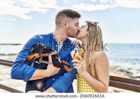 Young caucasian couple standing with dog eating ice cream at the beach.