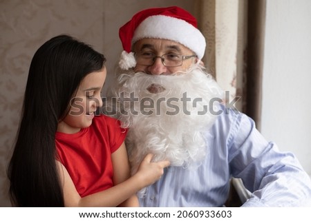 Picture of an elderly man wearing a Santa hat while playing with his grandchildren