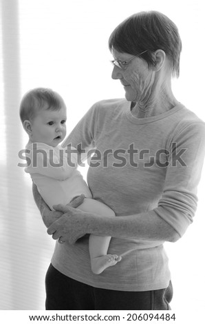 Happy grandmother holds her grandchild at home. Concept photo of newborn, baby, grandmother, grand motherhood, senior,retirement, lifestyle (BW)