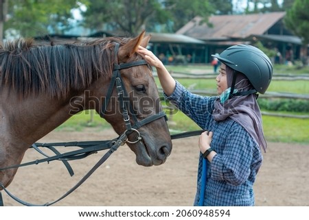 Asian girl stroking her favorite horse. bonding between horse and rider