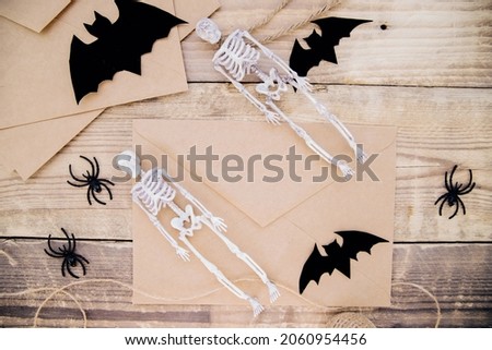 A kraft paper envelope and felt bats, skeletons, spiders around on a wooden background. Halloween decor. Handmade holiday decorations.