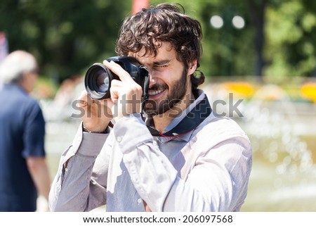 Smiling photographer using his camera Royalty-Free Stock Photo #206097568