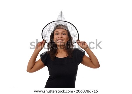 Isolated portrait on white background with copy space for Halloween ad of a beautiful woman smiling with beautiful toothy smile, wearing a witch wizard hat and looking at camera