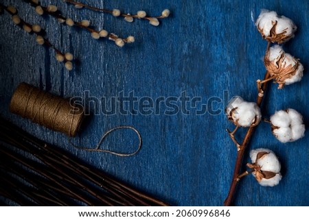 Blue wooden background with cotton flower, willow branch. Empty space 