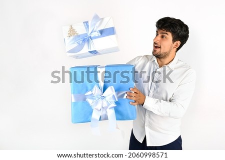 Happy young guy with 2 gift packages, blue and white box with blue ribbon. isolated on white background, copy space. Advertising image sales
