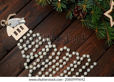 Christmas tree made of beads with the house with keys on the top and fir branches on wooden background