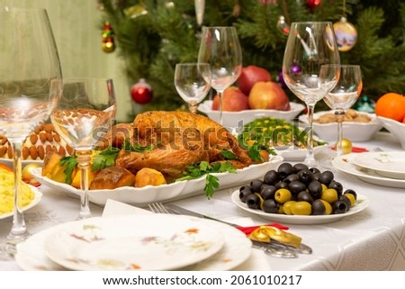 Festive Christmas served table against beautiful green pine tree decorated with many colorful new year toys. Xmas dinner, delicious food, christmas turkey. Winter holidays celebration at cozy home Royalty-Free Stock Photo #2061010217