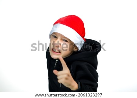 a boy in a red hat bent shows his index finger and threatens the camera shows his teeth