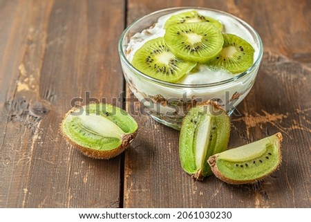 homemade delicious layered dessert of yogurt, muesli and kiwi fruit on a wooden table