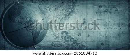 Ancient globe on the old map background. Selective focus on globe. Retro style. Science, education, travel antique background. History and geography team. Blue tinted.