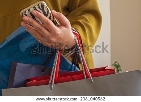 Mid-section portrait of stylish young woman holding shopping bags with Black Friday and texting on the go while leaving mall in sale season, copy space