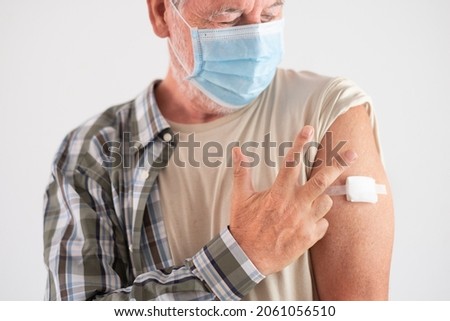 Portrait Close Up studio shot of old caucasian senior man patient wearing face mask showing with fingers number three as booster third doses of covid-19 vaccine. Against new omicron variant Royalty-Free Stock Photo #2061056510