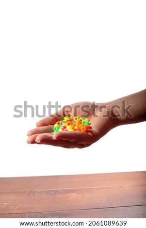 Woman's hand with a handful of colored pearls for handicrafts or decorations. Isolated on white background.
