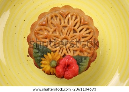Colorful flower decorated moon cake Chinese mid autumn festival tea on yellow ceramic plate