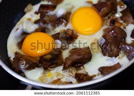 Eggs with mushrooms frying in pan in kitchen, nobody