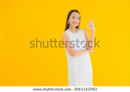 Portrait beautiful young asian woman in action on yellow isolated background