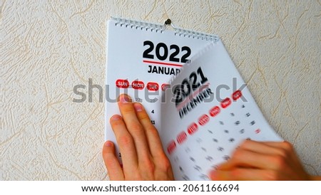 Close-up of a man's hands tearing off the December page of a 2021 calendar on the wall followed by the January page of a new 2022 calendar Royalty-Free Stock Photo #2061166694