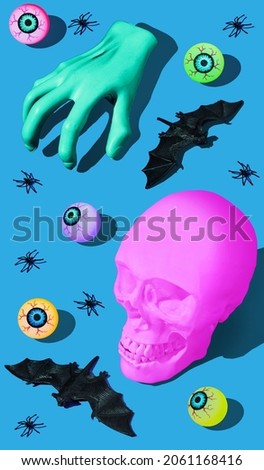 Halloween horror concept with pink skull, zombie hand, spiders, bats and eyeballs. Blue background