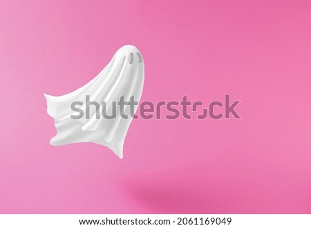 White ghost sheet costume against pastel pink background. Minimal Halloween scary concept.