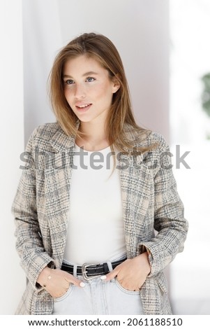 A modern business woman in an office with a neutral background. A young girl, a break at work, a work situation.