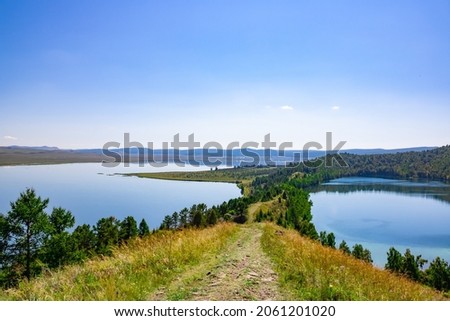 Panoramic photo from a height. Blue lakes, sky and mountains. Beautiful summer landscape. Scenic. Lake Krugloye, Lake Maloe, Mountain range of the Kuznetsk Alatau