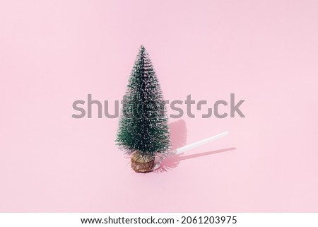 A Christmas and New Year tree with snow stands on a white plastic fork on a pink background. Minimal design. Copy space.