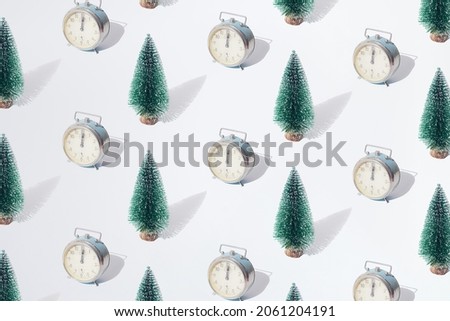 Arranged green New Year and Christmas tree with old silver retro watch with hand on twelve midnight hour on a white pastel background. Pattern.