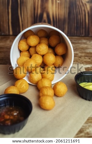 Close-up of potato balls prepared in a fast food restaurant. Barizl national cuisine. Food in a cardboard box. Takeout food. Round buns with potatoes and cheese.