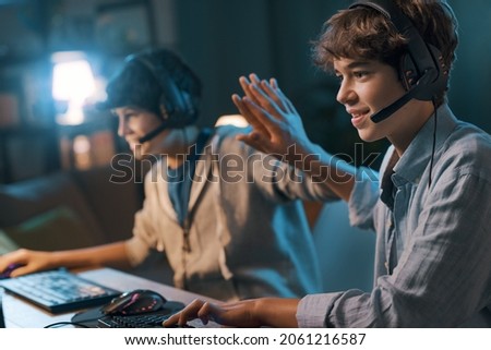 Cheerful friends playing online video games together and winning, they give a high five
