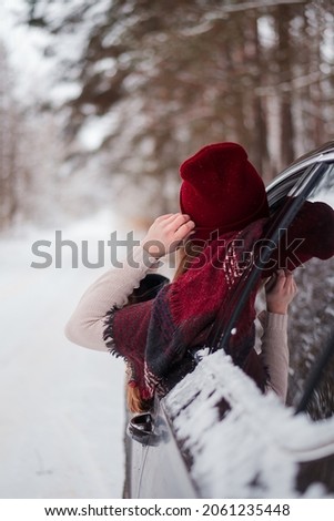 The girl in the car in winter. Winter forest. Lots of snow. Beautiful girl in the car window.