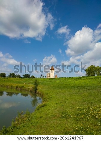 a small white church stands by the lake on a hill