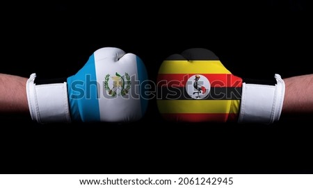 Two hands of wearing boxing gloves with Uganda and Guatemala flag. Boxing competition concept. Confrontation between two countries