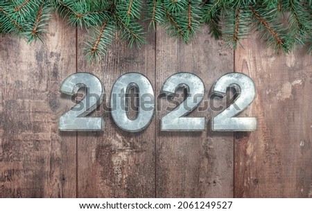 Happy new year 2022 text on wooden rustic table with branches of Christmas trees. New Year greeting card. Inscription Happy New 2022 Year on wooden table
