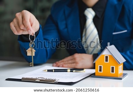 Real estate agent passing keys to his client, Hand of real estate agent passes the key to new homeowners in office with buyer house concept.