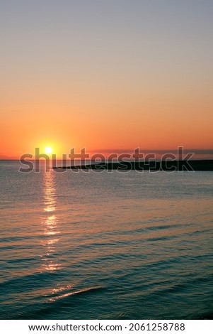 We are on the Salento coast Tarantina, the autumn sun sets behind the mountains of Basilicata visible in the background, vertical image. Royalty-Free Stock Photo #2061258788