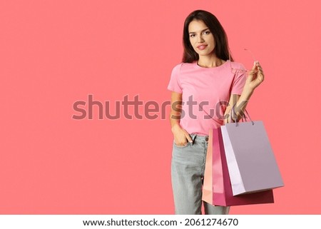 Attractive girl with multicolored paper bags on pink background.