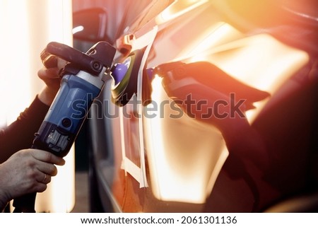 Master mechanic polishes red car with polisher, detailing series. Royalty-Free Stock Photo #2061301136